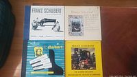 Four Franz Schubert vinyl record albums arranged on wooden surface, showing cover artwork and titles