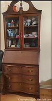 Front view of the closed secretary china cabinet showing glass doors on top, drop-front desk, and curved drawers beneath