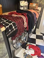 Several scarves and casual tops of various colors arranged on top of a front-loading washing machine and dryer unit.