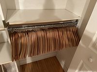 Photo showing 45 wooden hangers on a closet rod, mostly curved style with a few straight ones, natural wood finish and metal hooks.