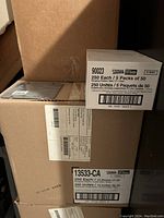 Boxes of hanging folders and hanging folder tabs stacked with labels showing quantities, product IDs, and Staples branding.