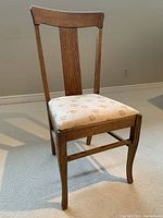 Full view of antique oak chair showing its shape and floral upholstered seat.