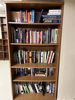 Front view of the large wood bookcase filled with various books on five shelves