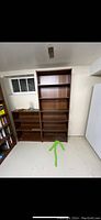 Full view of a large wood bookcase with five shelves in a basement setting, showing clean lines and dark brown finish.