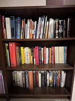 Three shelves of books in a wooden bookcase showing a variety of subjects and conditions