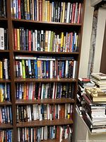 Six-shelf bookcase filled with assorted books and a side stack of volumes