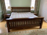 Wide view of king bedframe showing slatted headboard and footboard with two nightstands