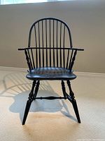 Front view showing bow back spindles, saddle seat, scrolled arms, and turned legs.