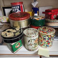 Photo showing assorted collectible tins including floral designs, butterfly motifs, cat and oatmeal themed tins.