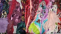 Multiple ladies scarves in pink, red, purple, green and multicolor arranged side by side showing different materials and styles.