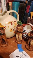 Photo of three carved wood cowboy figurines with Hall's floral water pitcher in the background