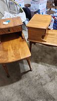 Pair of matching maple end tables with single drawer and lower shelf, shown together on carpet.