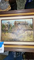 Photo of a matted and framed oil painting depicting a rustic barn with windmill and water tower, surrounded by nature.