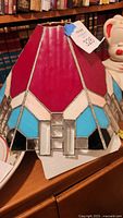 Full view of stained glass Tiffany style lamp shade showing colorful geometric pattern with red, blue, white, black, and clear glass panels.