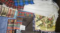 Multiple scarves including plaid, patterned, white lace shawl, and Montana silk scarf showing overall lot contents