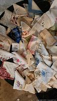 Photo showing a pile of assorted women's handkerchiefs with various floral embroideries and lace edges