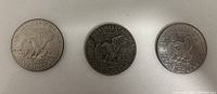 Reverse sides of three Eisenhower dollar coins showing the eagle landing on the Moon design.
