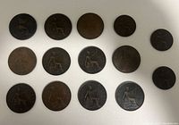 Collection of 15 early British penny and half penny coins laid out on a white background showing seated Britannia reverse design.