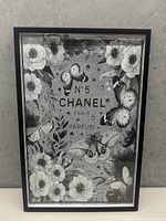 Front view of framed Chanel No. 5 floral and butterfly wall art in black and white.