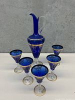 Full view of decanter and five matching cobalt blue glasses with gold embellishments