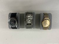 Photo of 3 watches displayed on gray pillows showing variety of styles including diver watch, Boyd London, and Casio