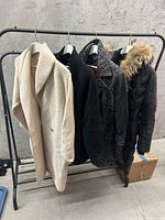 Four women’s jackets hanging on a rack against a grey background showing colors and styles