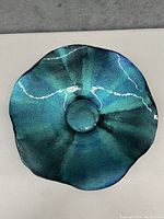 Top view of the blue glass bowl showing its circular depression and wavy rim with iridescent blue-green finish.