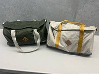 Two Herschel duffel bags side by side, showing colors and overall style.
