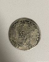 Obverse side of silver coin showing crowned shield with heraldic symbols including lion and castle.