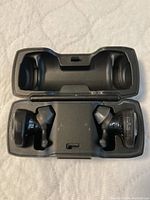 Open charging case with Bose Sport Earbuds inside, showing left and right earbuds fitting in molded slots