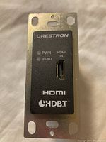 Front side of Crestron HDBaseT transmitter wall plate showing HDMI input, power and video indicator LEDs, with metal mounting frame.