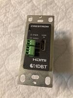 Front view of Crestron transmitter module showing HDMI input and terminal block connectors for power, video, and communication