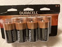 Front view showing 8 D size Duracell Coppertop batteries in blister pack with copper tops and black bodies.