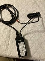 Top view showing power supply label with specifications and certification marks, connected cables including output cable with orange connector and power cord with plug.