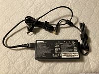 Full view of Lenovo 135W AC adapter with power cords laid out, showing plug types and Lenovo label on the brick.