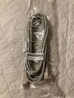 Packaged gray Ethernet patch cable with label showing Polycom part number 2457-40305-003PLE and barcode, cable coiled.