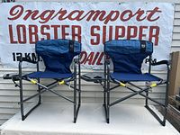 Two blue Timber Ridge folding camp chairs with black steel frames sitting side by side, showing overall structure and design.