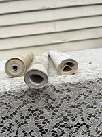 Close up of rolled vintage lithograph Florentine wallpaper sheets showing roll ends and some aging on paper edges.