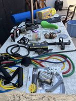 Overview photo of all items laid on table including bike tools, resistance bands, yoga pillow, and massage roller.