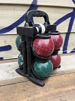 Red and green resin bocce balls arranged in black plastic carrying caddy with handle, showing size and design with white line pattern.
