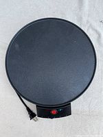 Top view of the round non-stick surface of the electric crepe maker showing the cooking surface and attached power cord.