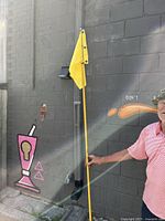 Golf flag held vertically against wall, showing full pole and flag length