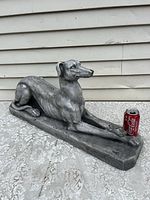 Side angle shot of the reclining greyhound statue showing length, texture, and minor damage on the ear.
