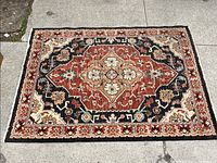 Top-down view of the carpet fully laid out on pavement, showing pattern and condition.