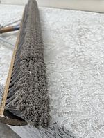 Close-up of dense bristles on a large hardwood broom showing condition and material.