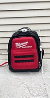 Front view of Milwaukee Packout backpack showing brand logo, black tool loops and size measurement of 19 inches tall and 25 inches wide