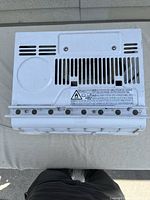 Top view of the air conditioner showing ventilation slots and model label area with caution stickers.