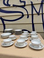 Photo showing cups, saucers, and side plates stacked and arranged on a chair.