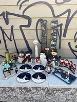 Overview from front of snowman and Christmas decorations arranged on table against siding.