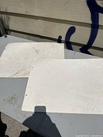 Two blank white rectangular boards likely used as backing for placards, showing dirt and scratches but excluding included tools.